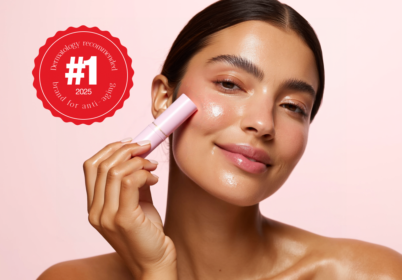 Woman applying sunscreen with a pink applicator on a pink background, featuring a dermatology recommended badge.