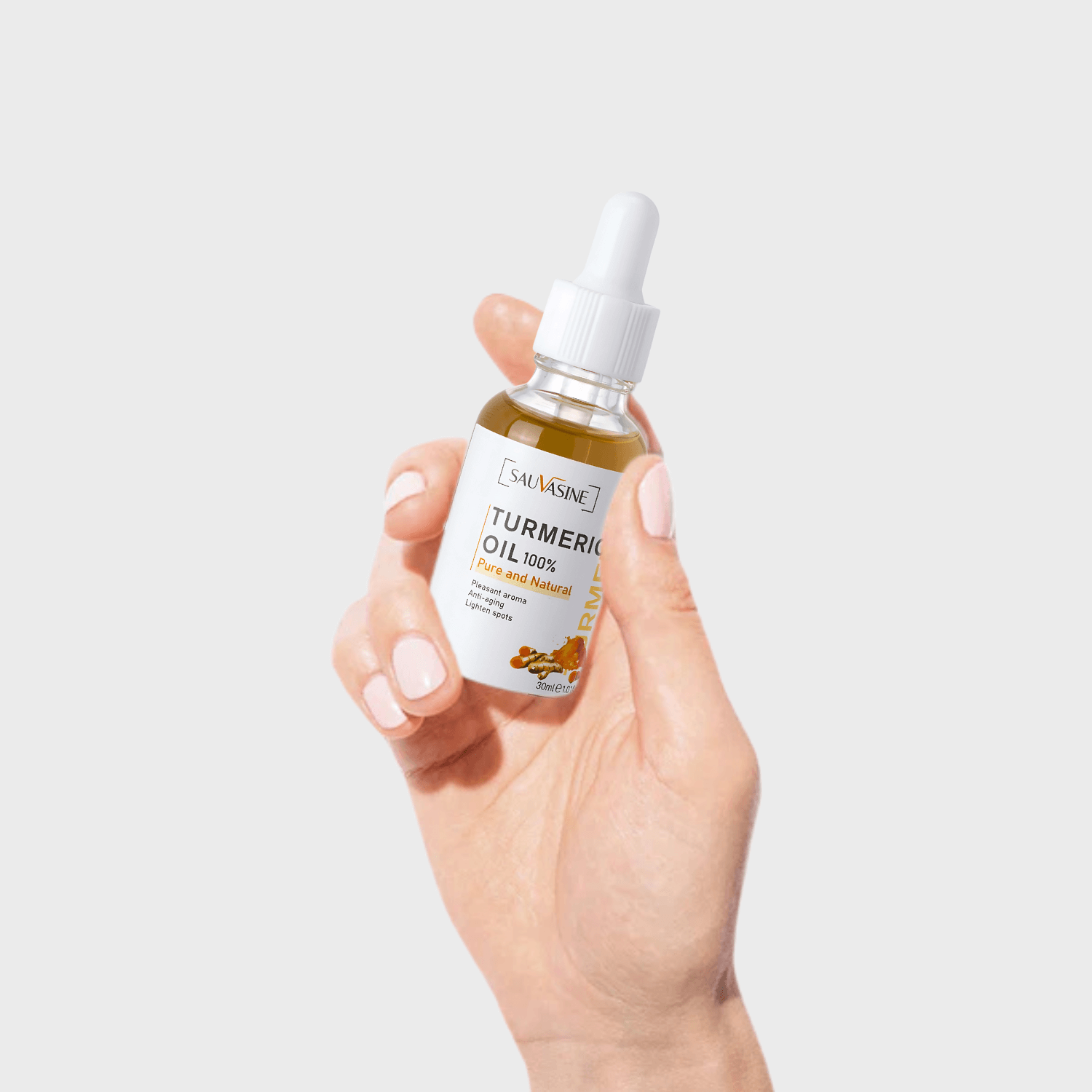 Hand holding a bottle of Salveine Turmeric Oil against a light gray background